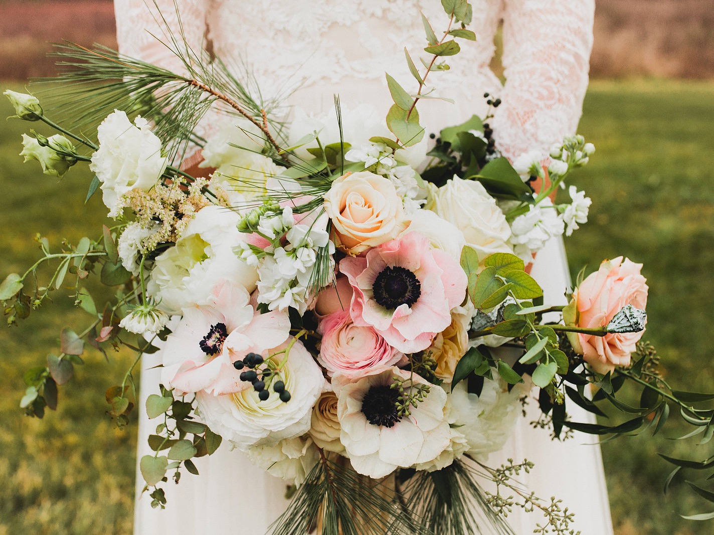 Natural white and pink winter wedding bouquet with anemones, roses and berries