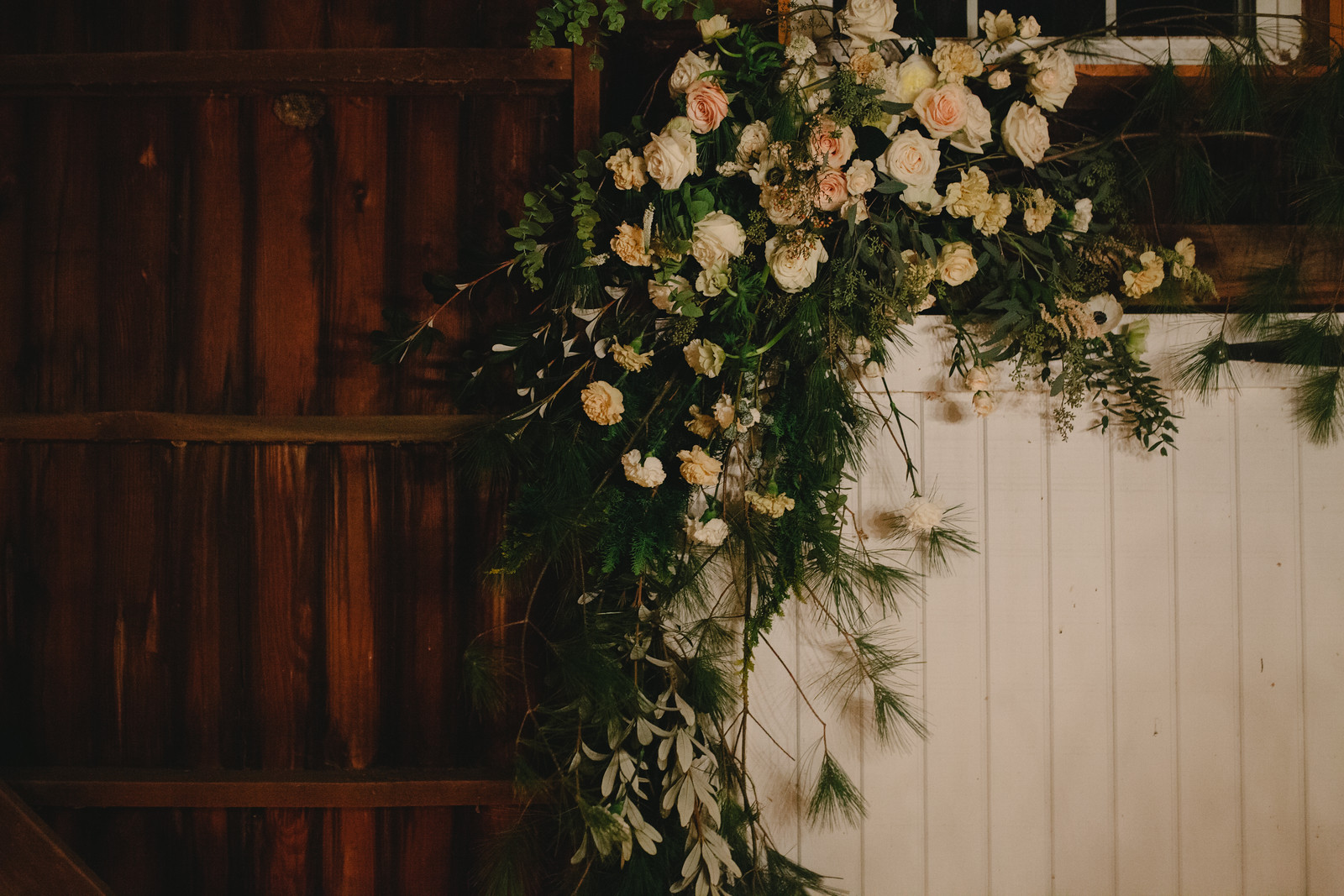 A natural wedding floral arch over a barn door for a winter wedding