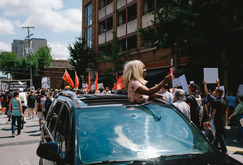 A woman records a march through Charlottesville by counter-protesters from a vehicle. (Seth Herald / The Atlantic)