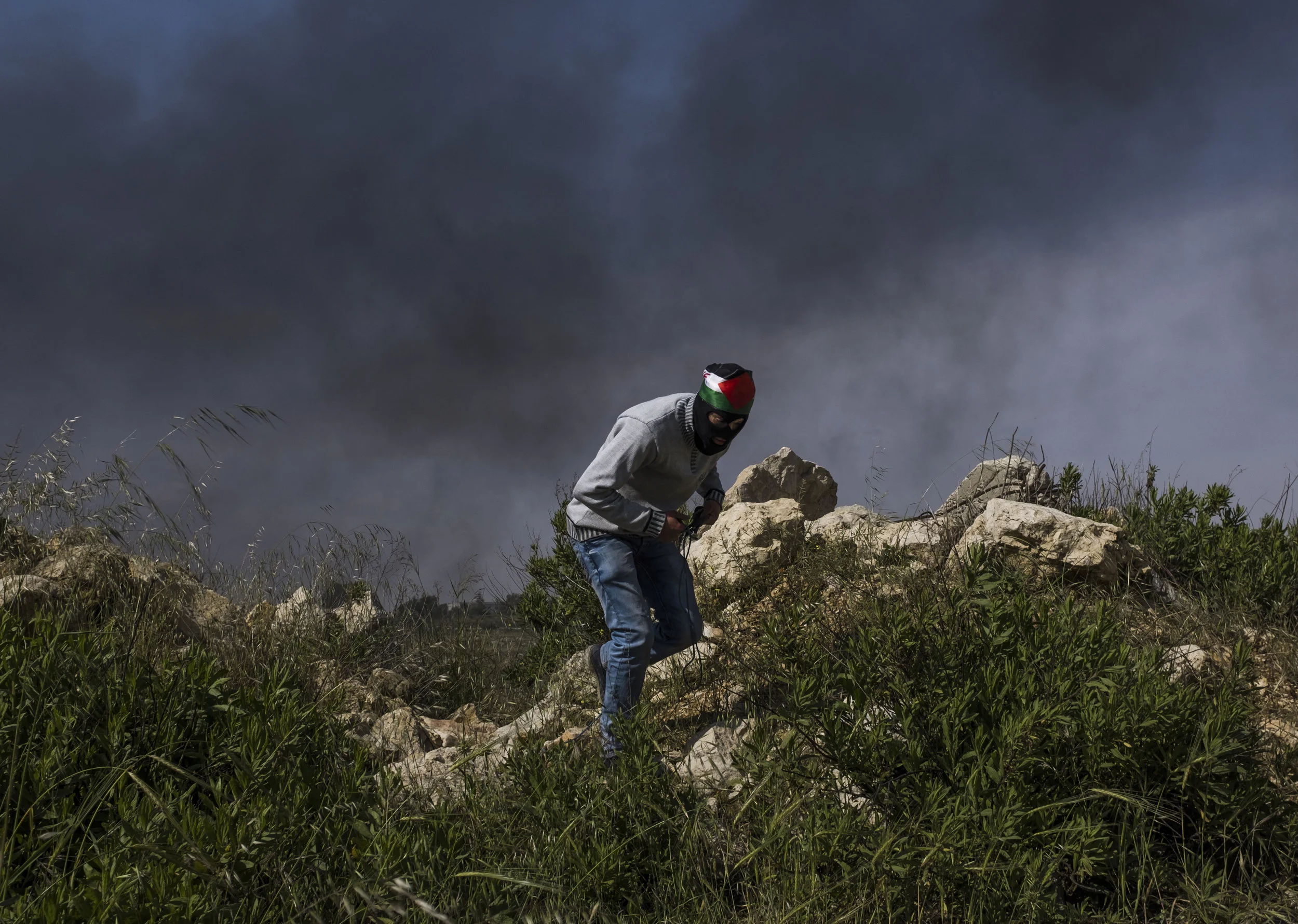 A Palestinian protester takes cover during protests and clashes with Israeli border Police near the Israeli settlement of Beit El on the outskirts of the West Bank city of Ramallah April 27, 2018. (Seth Herald/Redux)