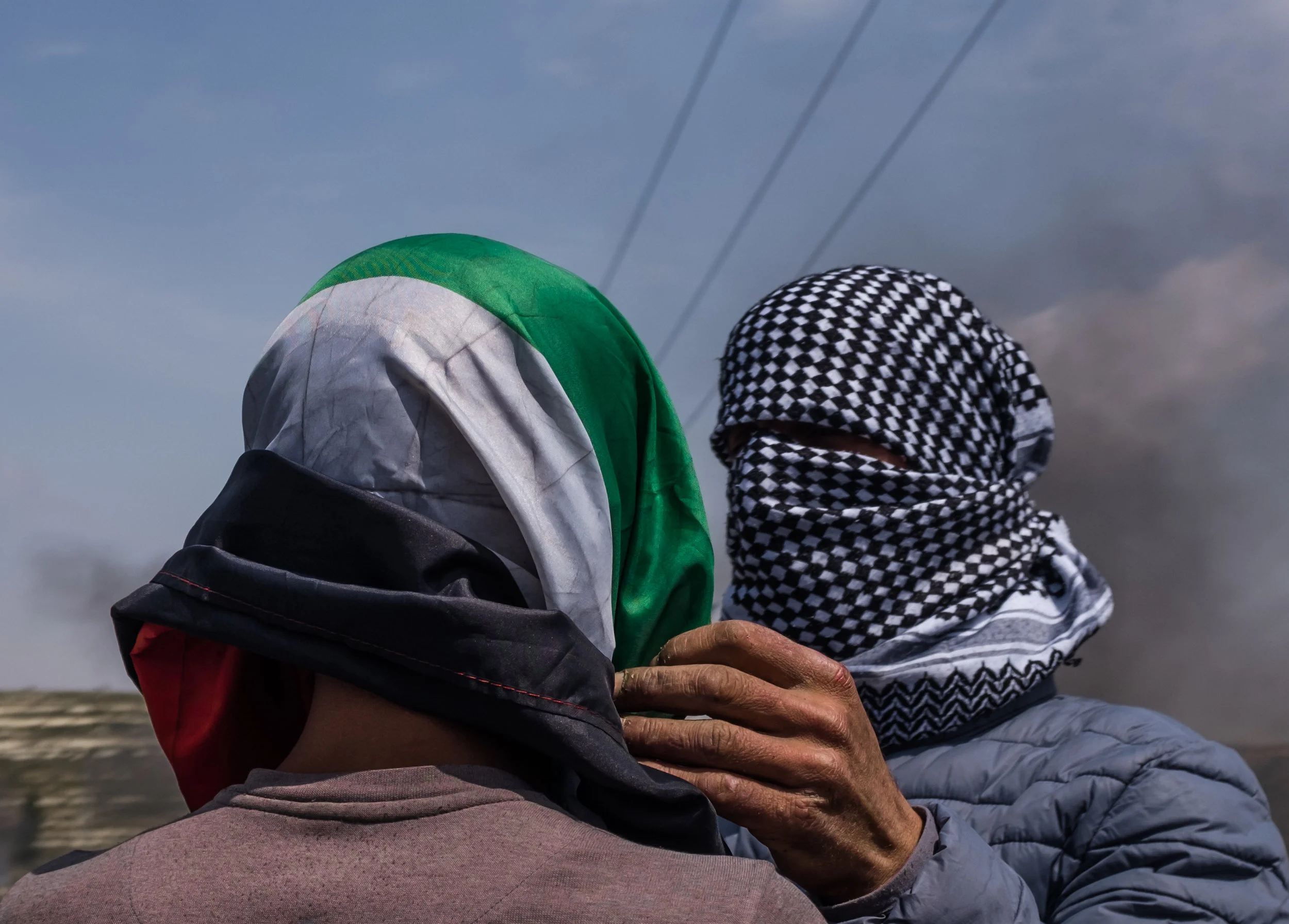 A Palestinian protester helps tie a Palestinian flag around the face of his friend to conceal his identity during protests and clashes near the Israeli settlement of Beit El on the outskirts of Ramallah in the West Bank April 27, 2018. Covering the face helps prevent being recognized by Israeli Border Police cameras which if recognized usually results in arrest later in the week, if caught Palestinian protesters face up to 20 years in prison. (Seth Herald/Redux)