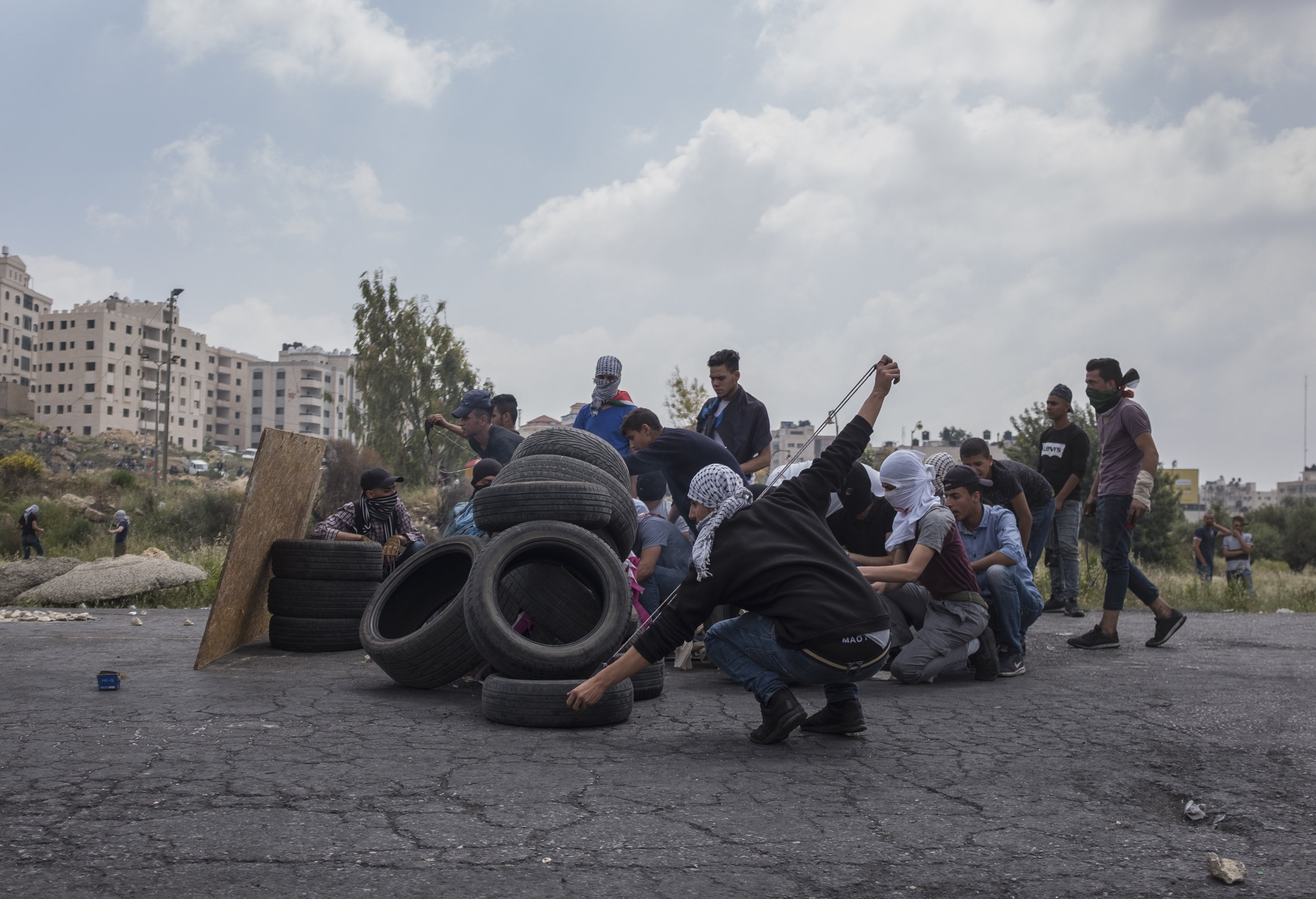 Palestinian protesters take cover behind tires during Nakba Day protests near the Israeli settlement of Beit El on the outskirts of the West Bank city of Ramallah May 15, 2018. Nakba meaning "Day of the Catastrophe" takes place on May 15 annually in commemoration of the displacement of Palestinians followed by the Israeli Declaration of Independence in 1948. (Seth Herald/Redux)