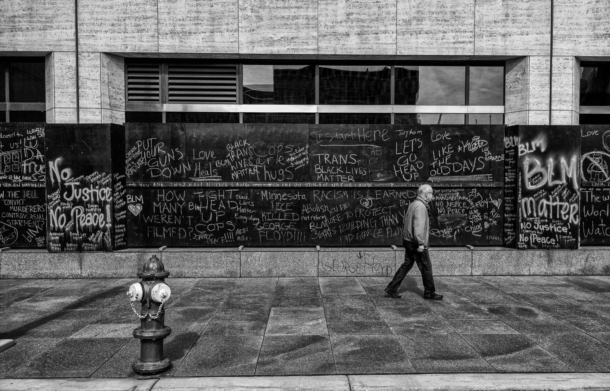  A man walks past boarded up windows near the Hennepin County Government Center where the Derek Chauvin trial is taking place in downtown Minneapolis, Minnesota, Saturday, April 17,2021.  (Seth Herald/Redux Pictures) 