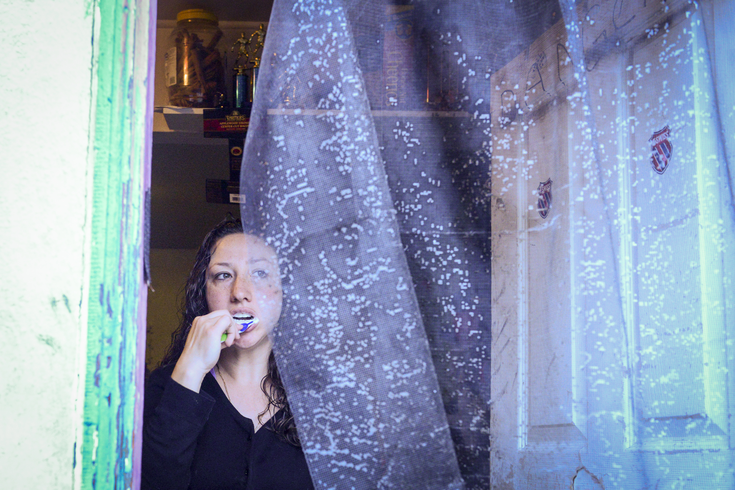 Amanda brushes her teeth while getting ready to go to work. She does not have running water in her home.