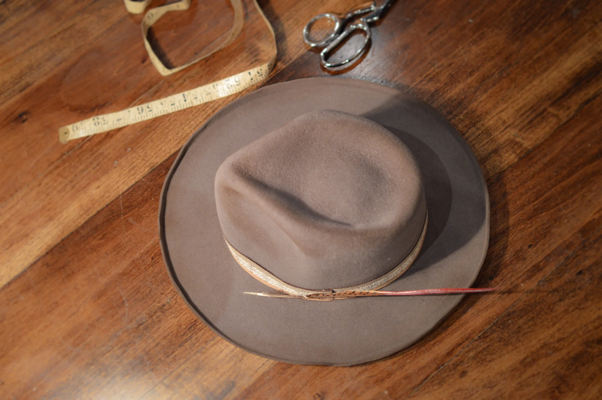 The Rustler in Mink - The Rustler has a 2 7/8 inch Kettle Curled Brim, with woven trim and feather.