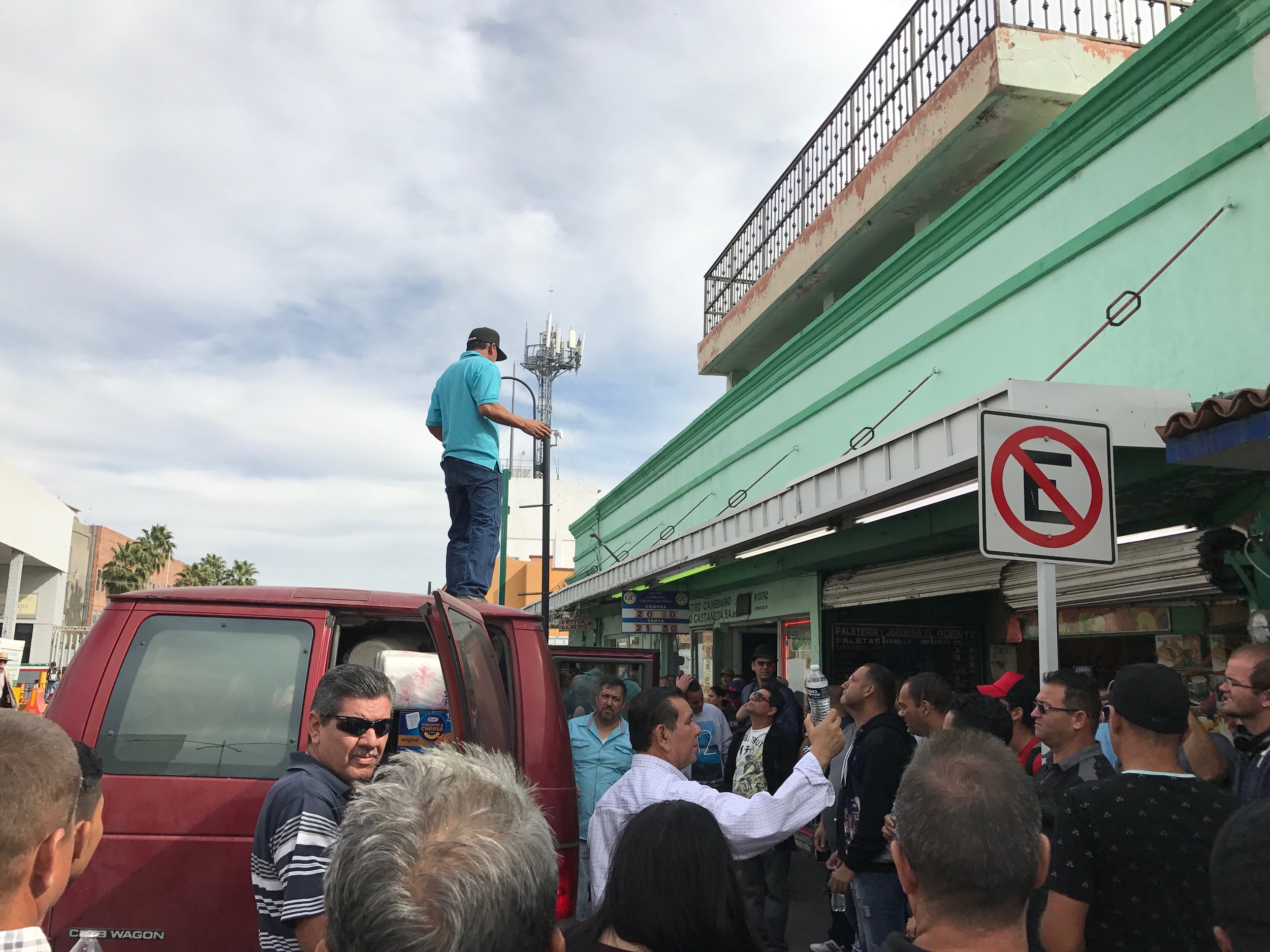  Arriving at a street corner in Nuevo Laredo with water to share, a pastor with the Baptist church network offers a blessing and prayer for the Cuban migrant community congregating in the streets.&nbsp; 