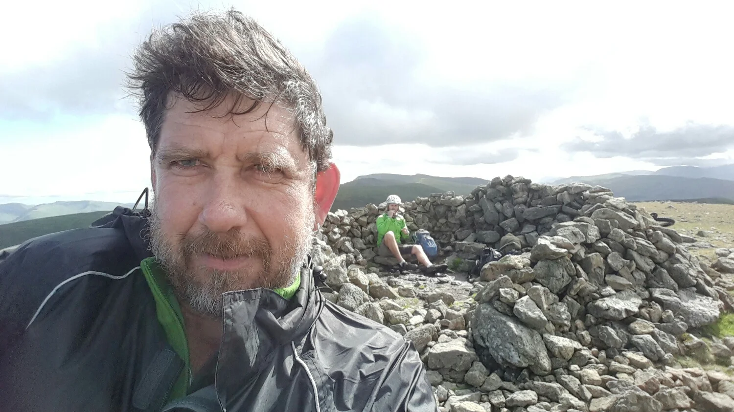 Like my new do? Pete sheltering in a rock Cain at the top of the hill while we have a bite to eat.