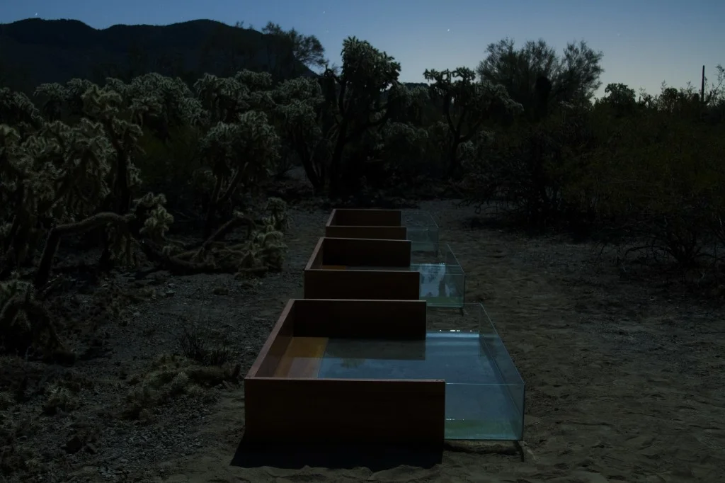 Installed Pray for Rain in the beautiful Sonoran desert, you must walk there by foot. The mahogany and glass pools glow in the moonlight and the water blows in the wind. The opening ceremony and party – equal parts drumming ceremony, reflective moon pools, clay sculpting, hand drilled torches and joyous celebration.
