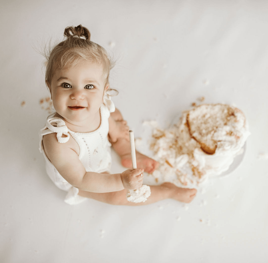 One-year-old baby playing with cake during a natural first birthday session in South Morang
