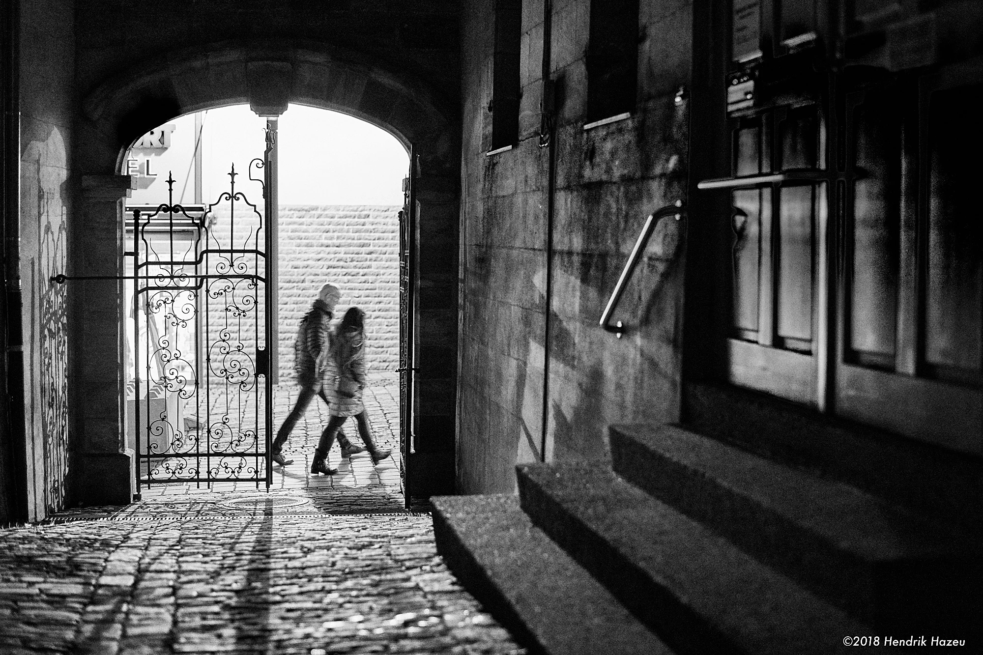 Two walkers before the gate. Nikon D850 & AF-S 58mm f/1.4G @f/2, 1/45 sec, 3200 ISO