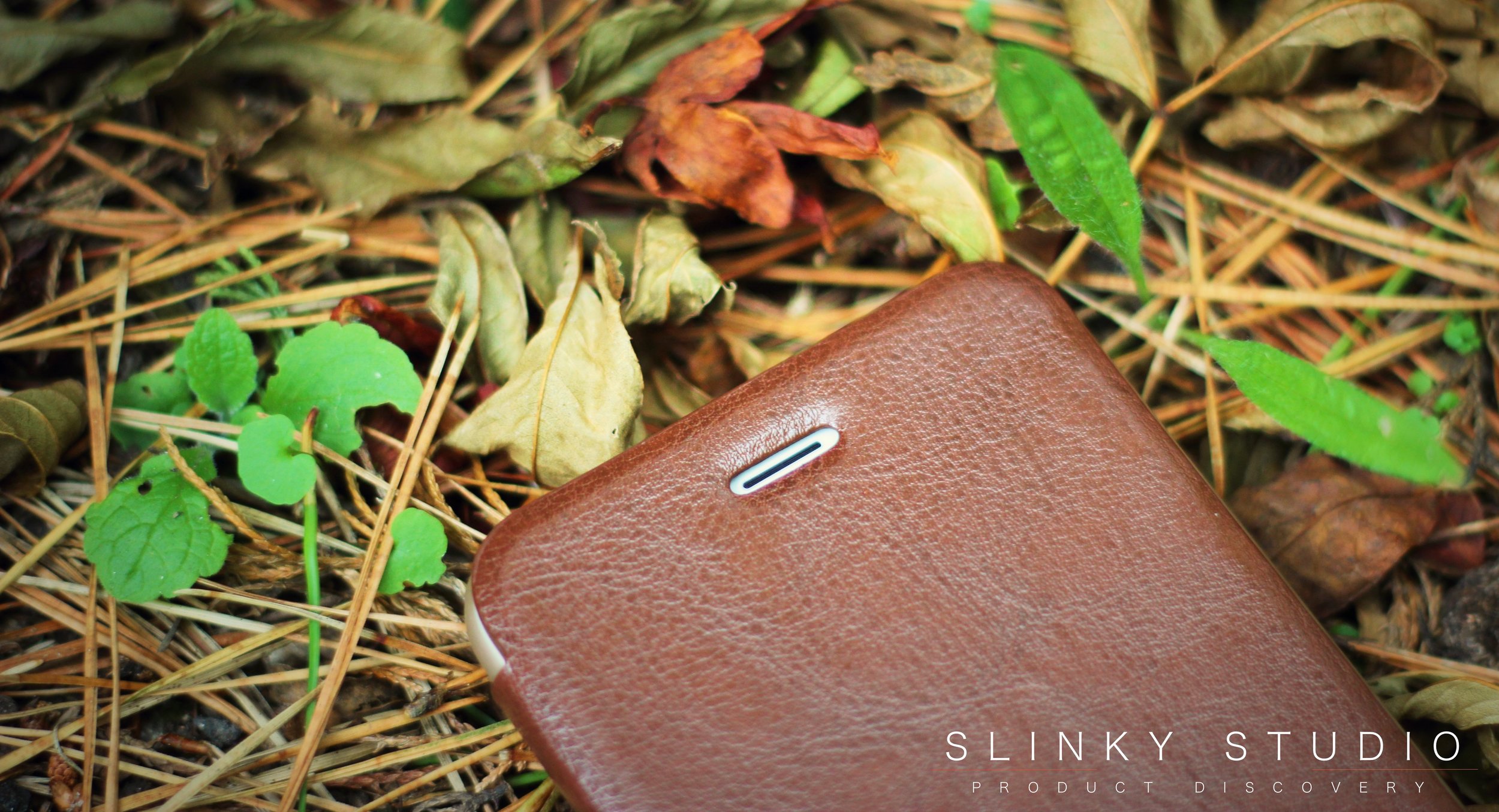 Elago Leather Flip Case for iPhone 6:6s Plus Front Speaker Cut Out Lying on Pile of Leafs.jpg