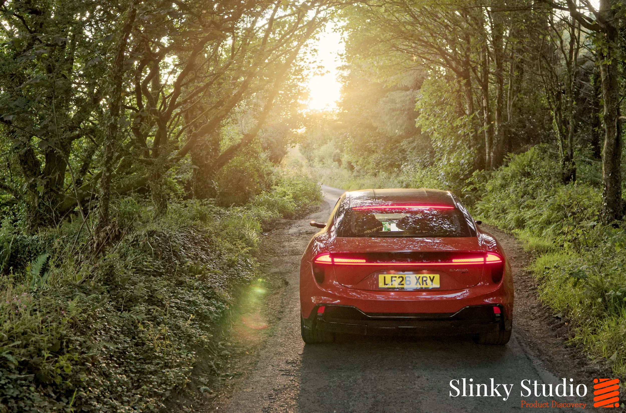Lotus Emeya Fireglow Orange Tail Lights Driving Through Woodland.jpg