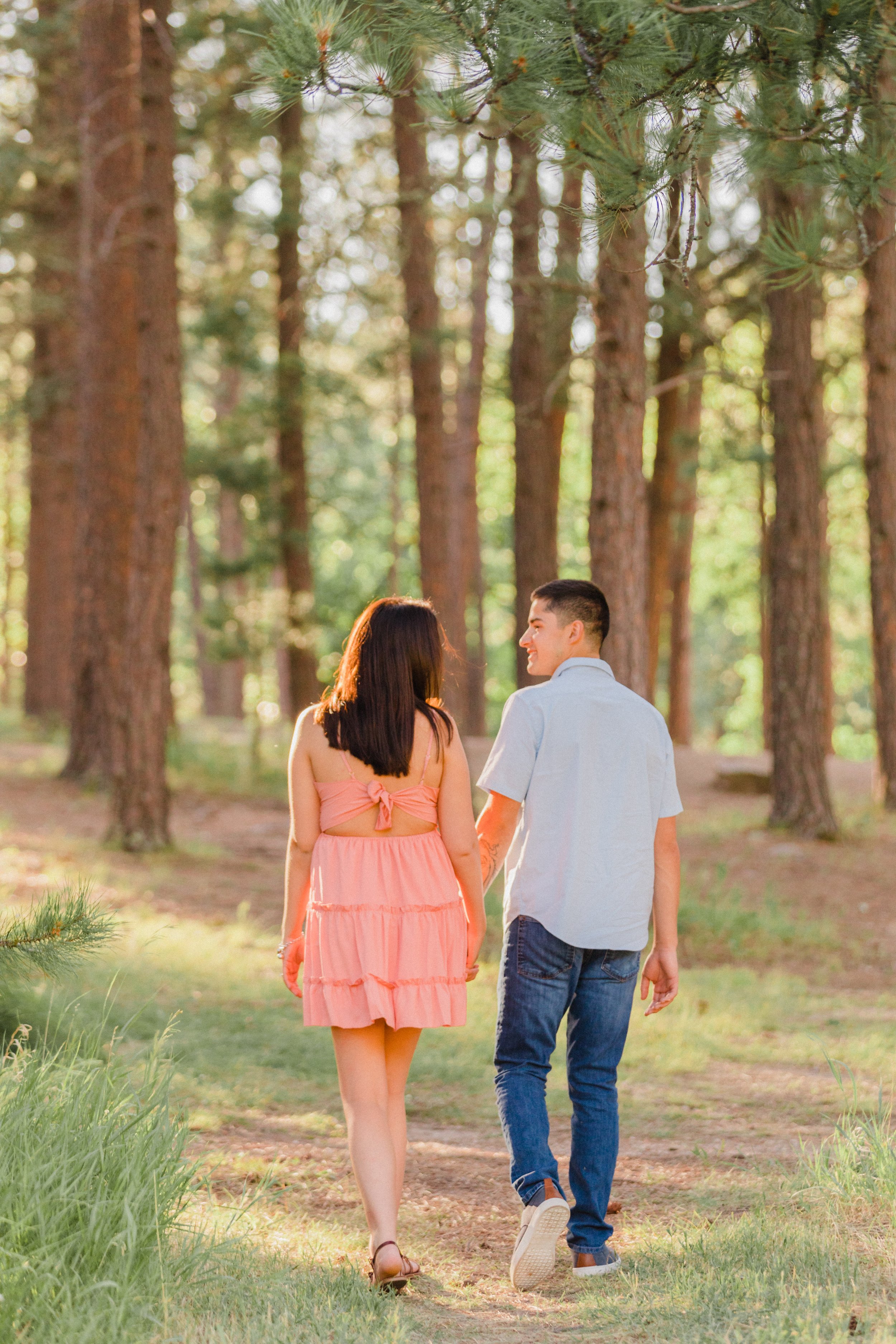 couple wearing pink and light blue walking in the woods at dalton lake
