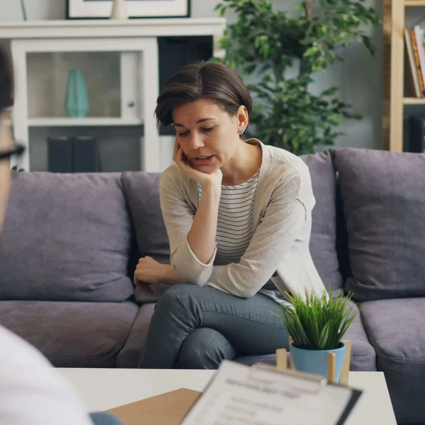 Woman sitting on a couch talking with her chin resting on her hand.