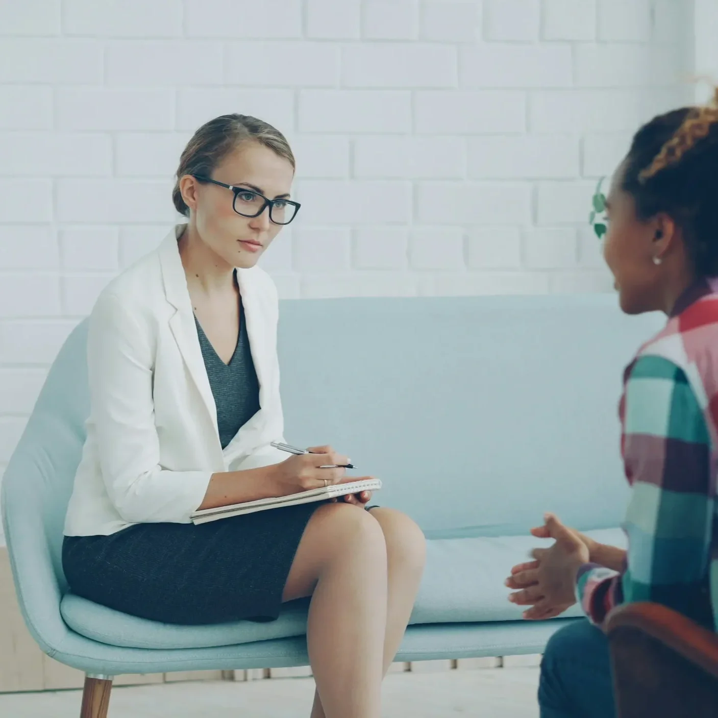 Seated therapist talking to woman.