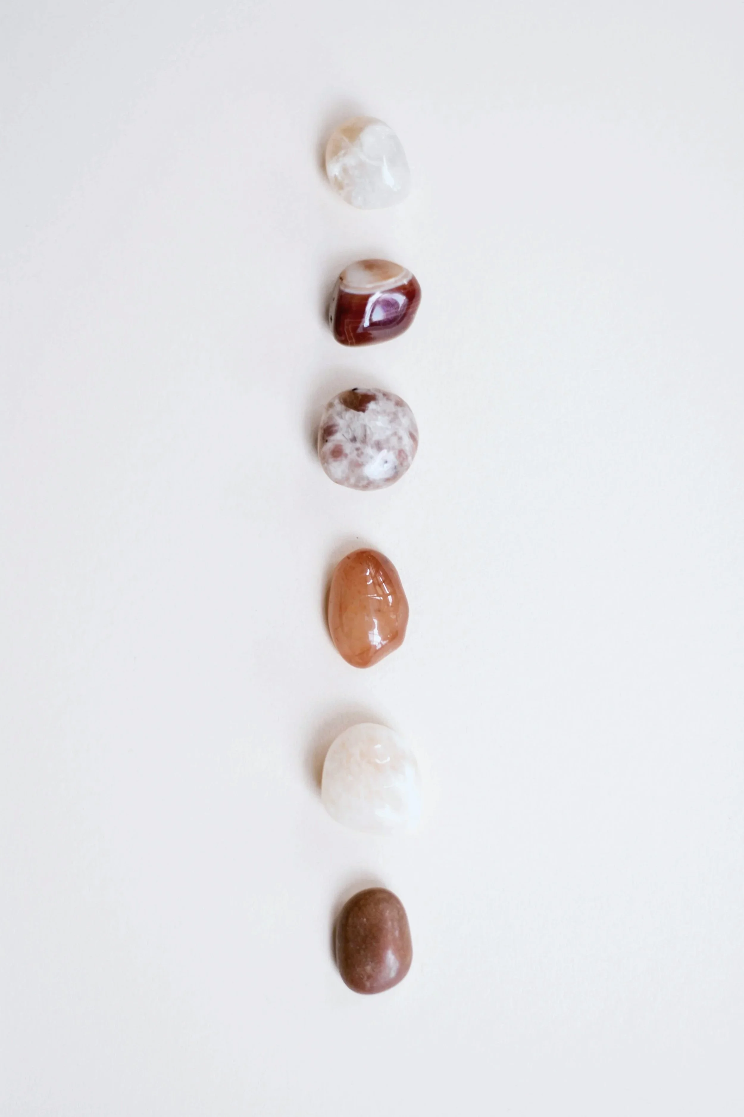 Six healing crystals in a vertical line on white background.