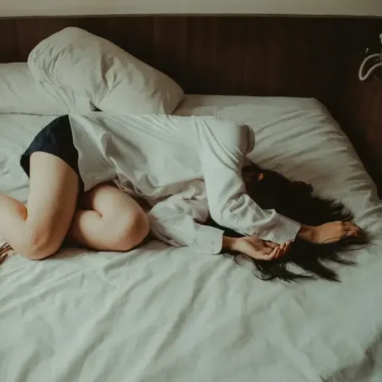 Woman curled up on bed.
