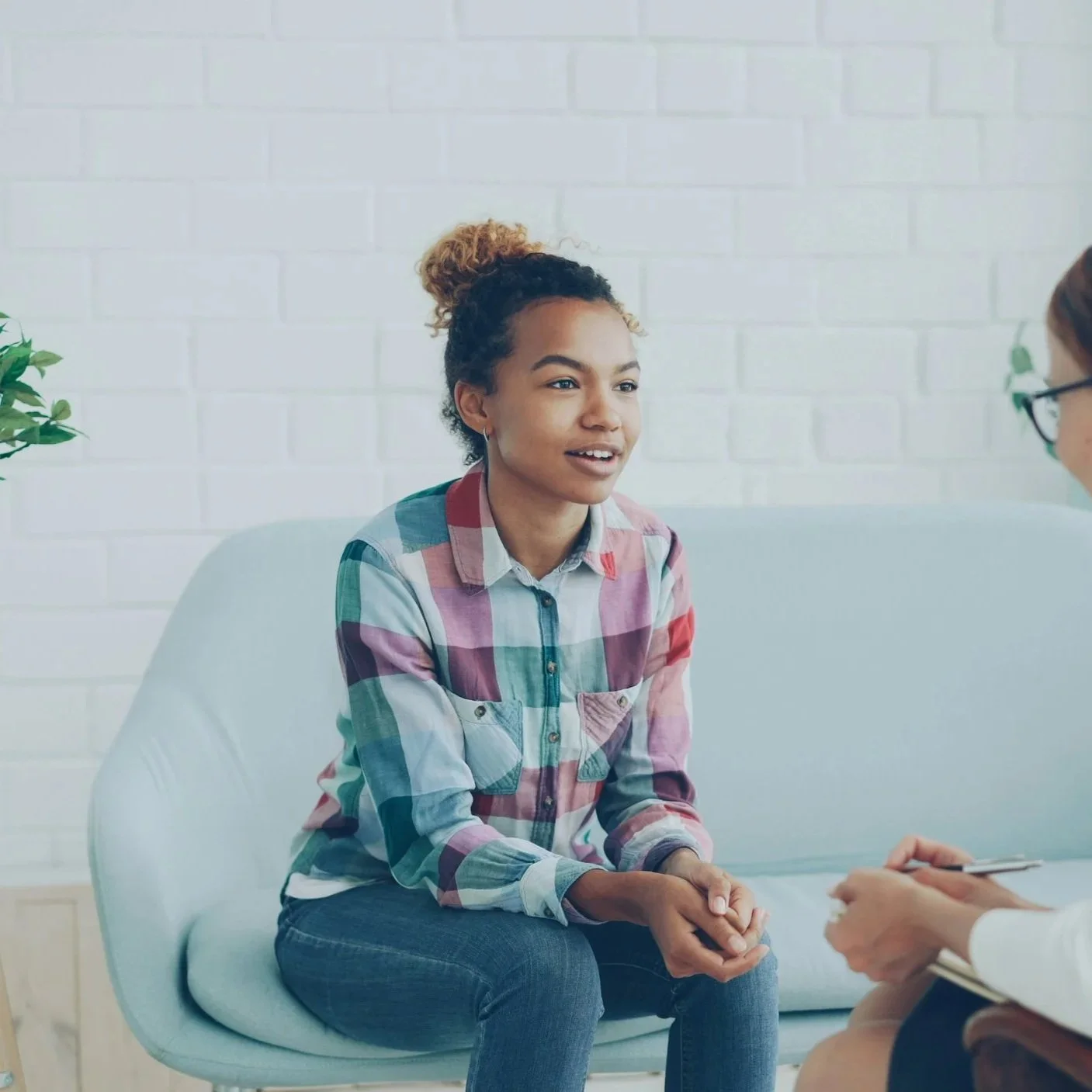 Young woman sitting and leaning forward talking to a therapist.