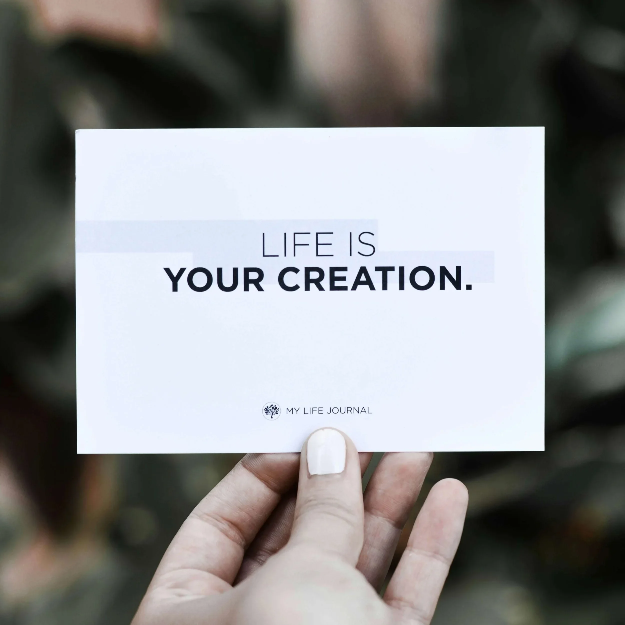 Hand holding card that says Life is your creation
