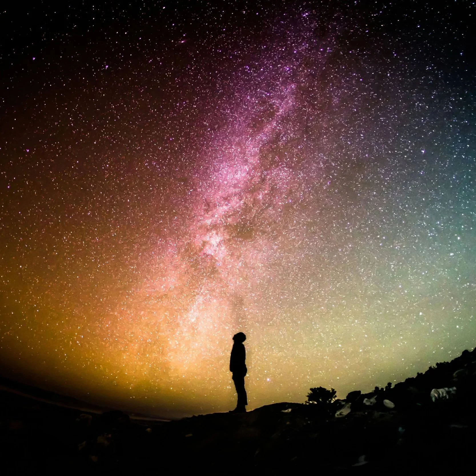 Person standing in the dark under the milky way in the sky.