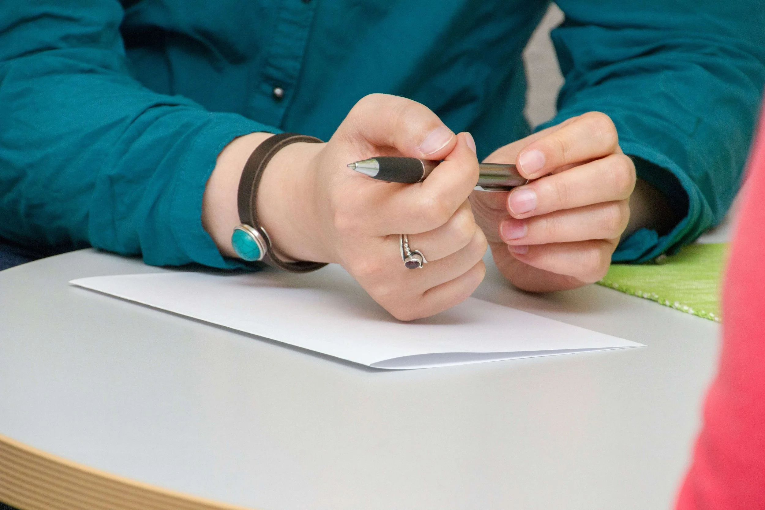 Woman's hands holding a pen with a blank piece of paper.