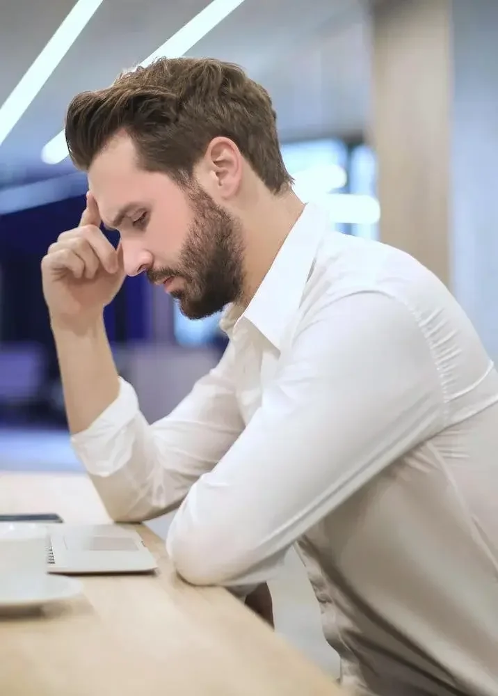 Man looking down with hand to head.