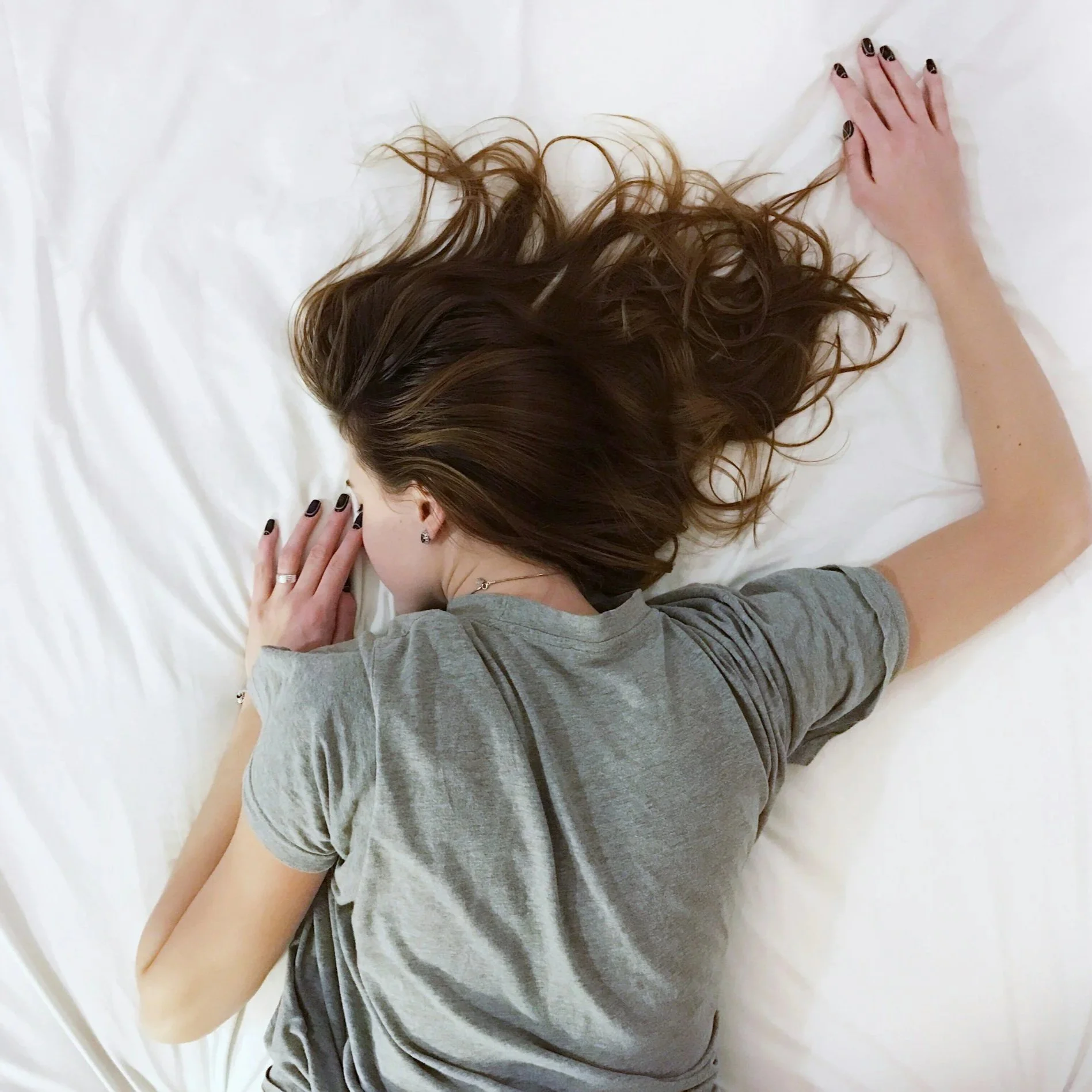 Woman lying face down in bed with outstretched arm