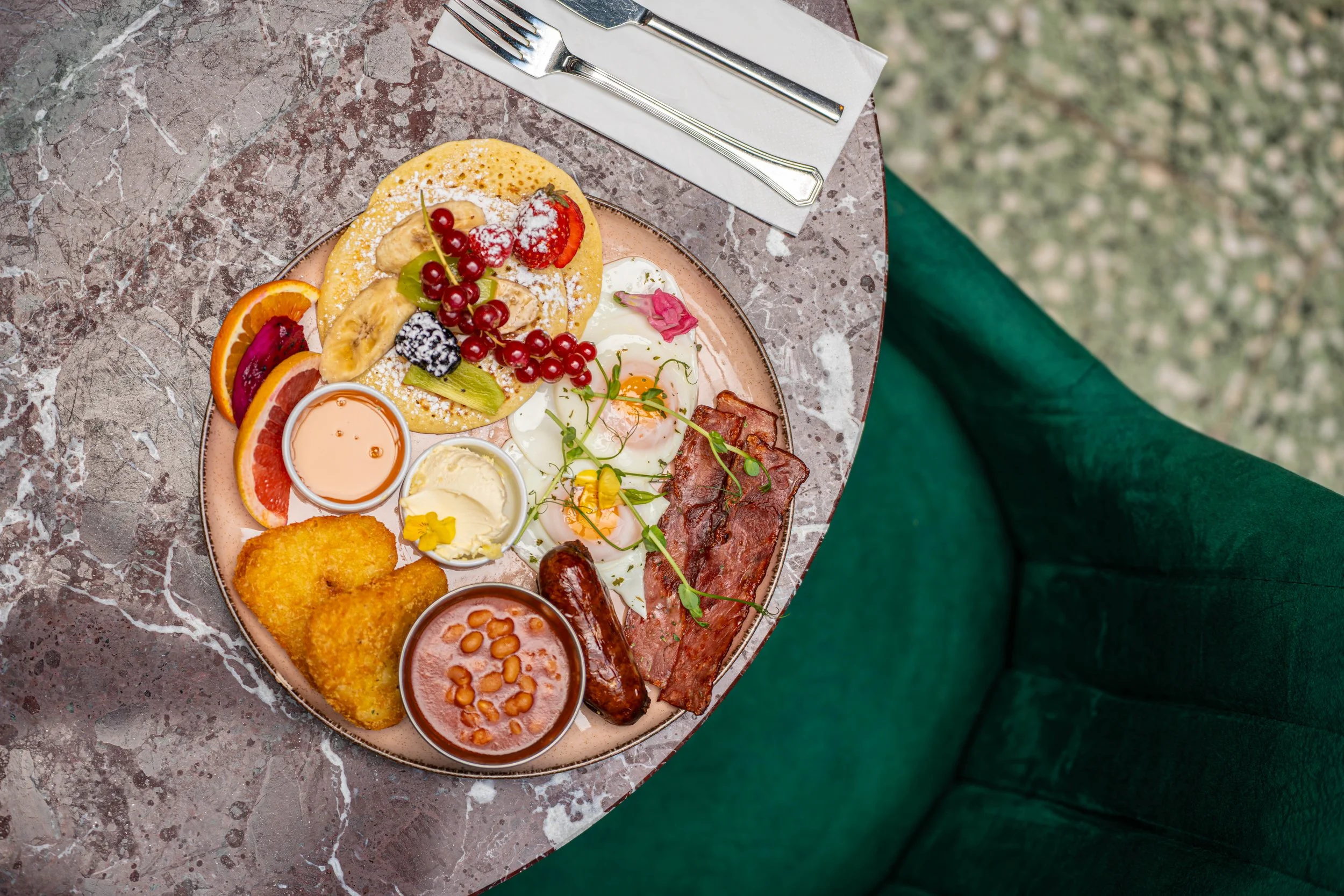 Overhead view of a breakfast platter with cured meats and fruit