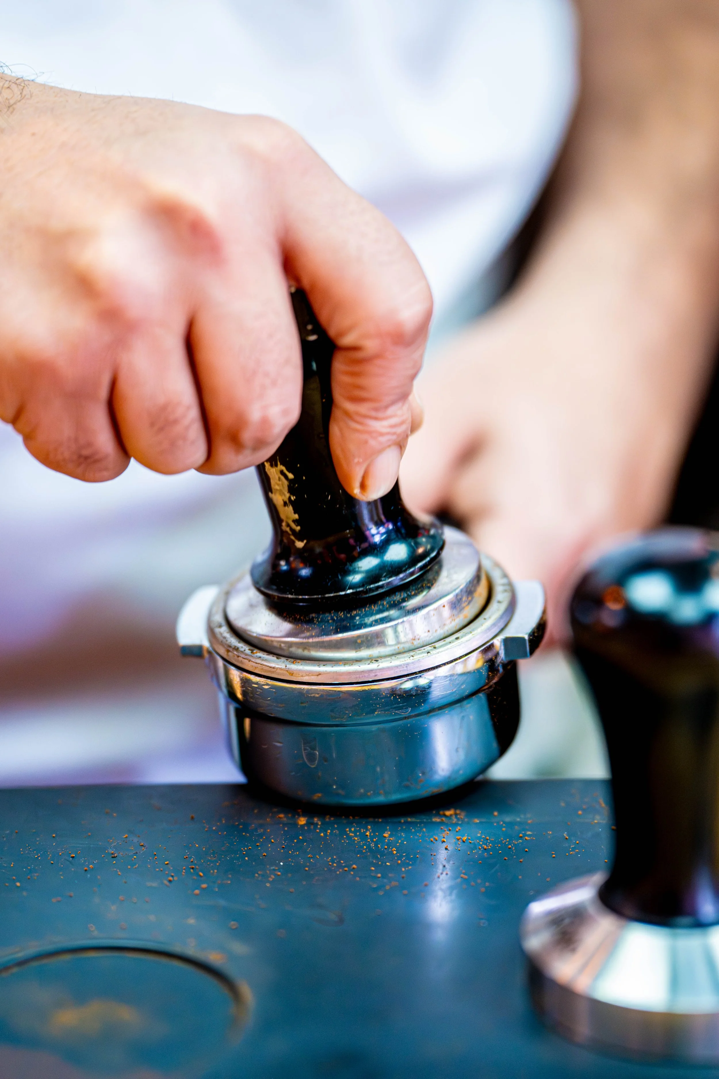 Barista tamping ground coffee before brewing espresso
