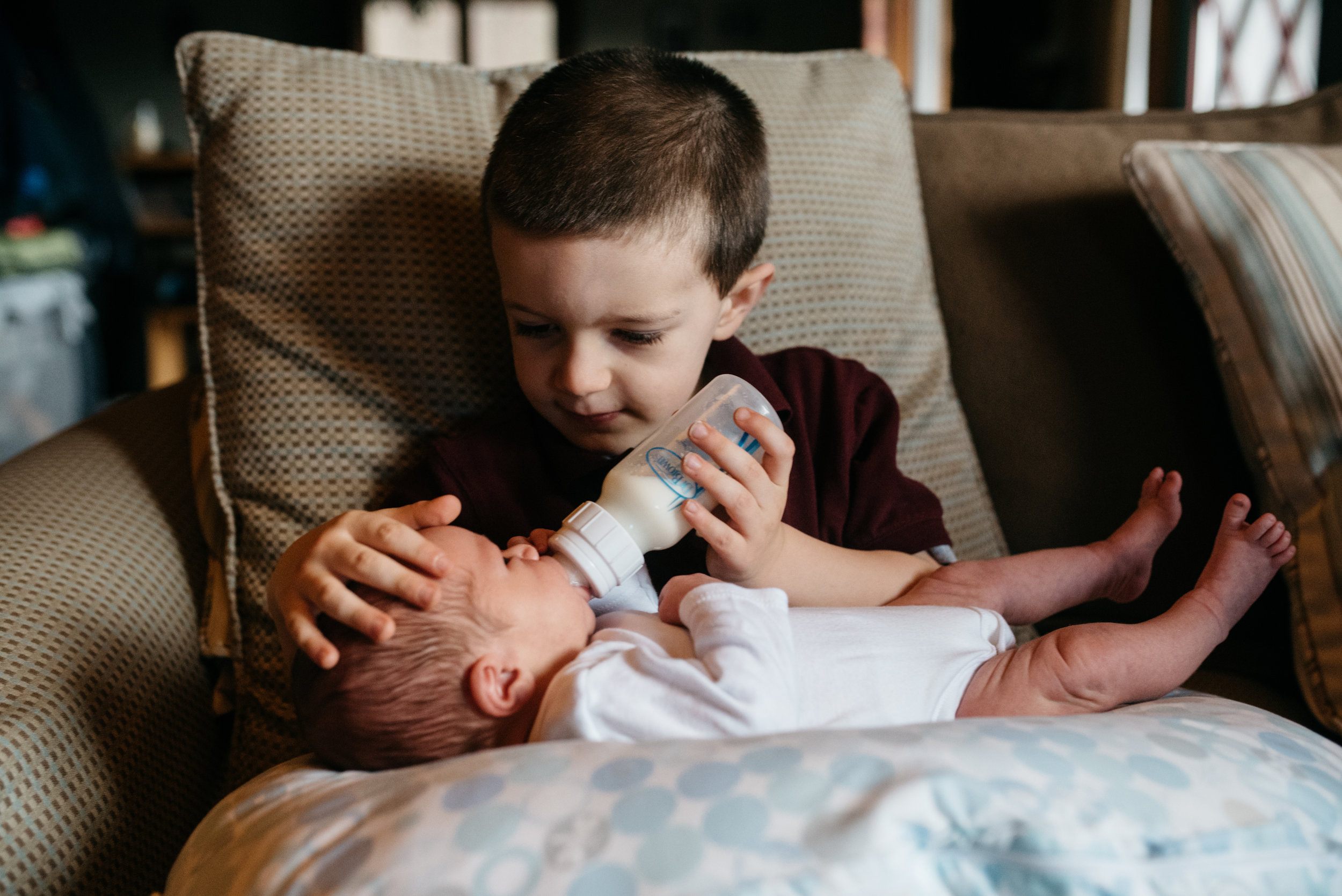 Brother feeding newborn brother lifestyle photographs