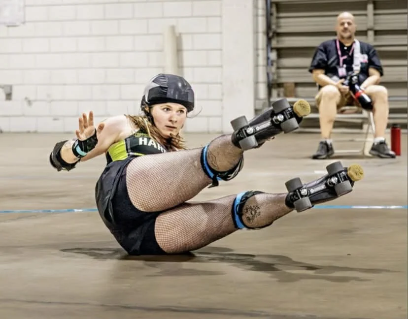 Panic as she has fallen to the ground while jamming. She is on her hip with her legs in the air, and her arms are out so she can call off the jam.