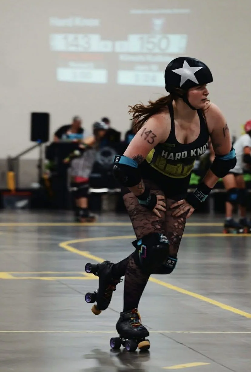 Panic is jamming and skating around the turn. Her number, 143, is clearly visible on her arm.
