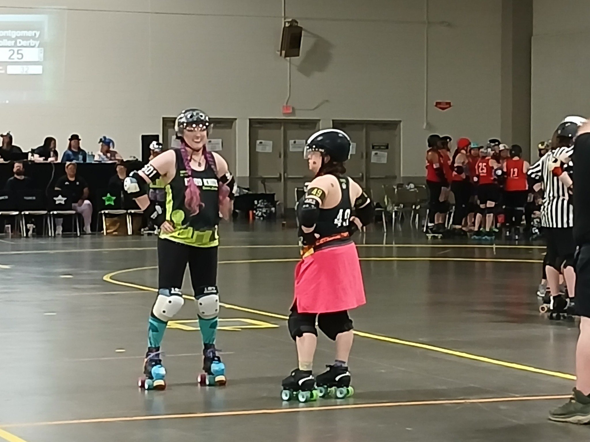 Death Starr and smalls waiting for a timeout to be over at a HKRD home bout. They are near the pivot line and both have their hands on their hips.