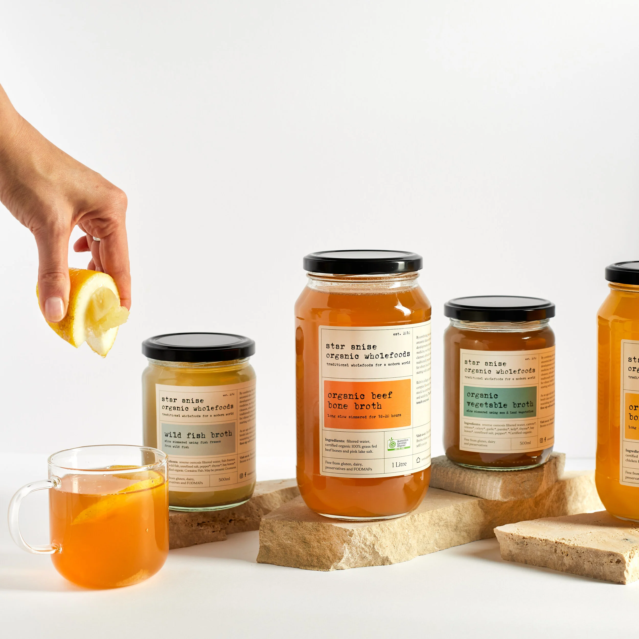 Serving beef bone broth with lemon, surrounded by full jar range – gelatin-rich and fridge-stable, Sydney delivery