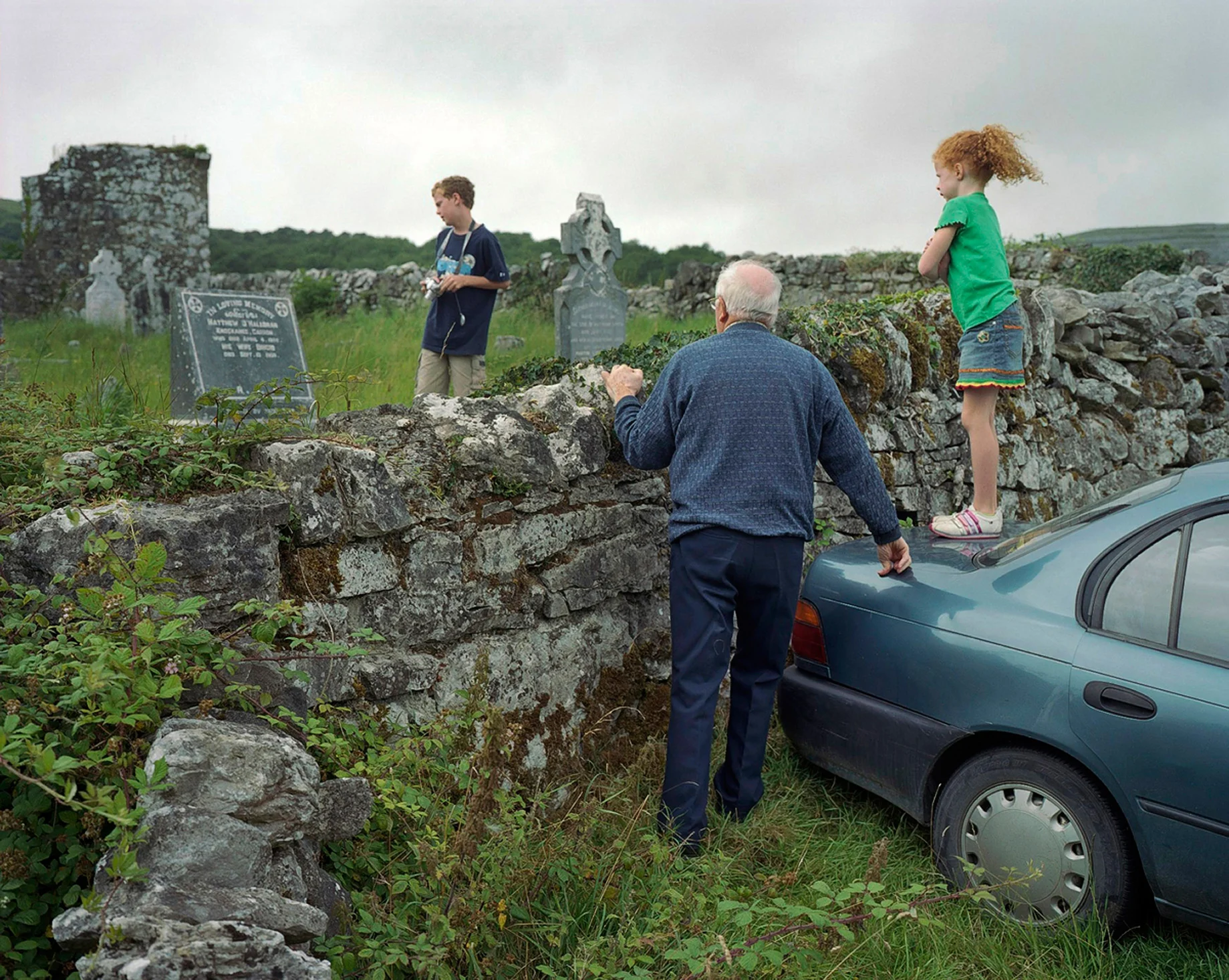 Though now a more secular society, Ireland still has remnants and relics of the old religious faith, even if many of its devoted followers are typically advanced in age – part of what might be termed a dying generation. The Catholic Church had been one of the country’s mainstays. Falling Mass attendances, declining priest numbers and various damaging scandals have shaken the institution and weakened its grip. Despite this my father is a daily Mass-goer; his faith doesn’t appear to have flinched. The house where I grew up in the west of Ireland is where my father now resides with his wife and their daughter Susan; all the rest of the family have flown the nest, some starting families of their own, one in New York where she has become part of the Irish Diaspora. The religious paraphernalia located throughout this house gives God a central presence and status not uncommon in Ireland at the time. We prayed as a family, like when the Angelus bells struck at noon and six in the evening. We knelt at night to say the Holy Rosary. Many of our rites of passage as children were rooted in Catholicism – our first communion, our confirmation, and so on. My father, who is 85, would not have seen anything remarkable in this. He was merely carrying on the tradition of his own father’s generation. Having spent half his life working, he recently retired, closing his drapery store. His undertaker’s business continues. For me and others in the family it meant that death was never far away or overtly mysterious. We became accustomed to the dead of our parish being prepared for the final ceremonies before burial. We would often come home from school to see who had died that day. If we truly wanted to make our father proud, we would have mastered the game he followed all his life: hurling. This ancient Irish sport, requiring great dexterity, courage and speed, can still weave a spell on him. Born in a rural community he has seen his own life change and now that of his children too. In recent years he lost a brother to whom he was close. Now I see him deriving great joy from his grandchildren. In their company he seems tranquil. At peace. His work done.