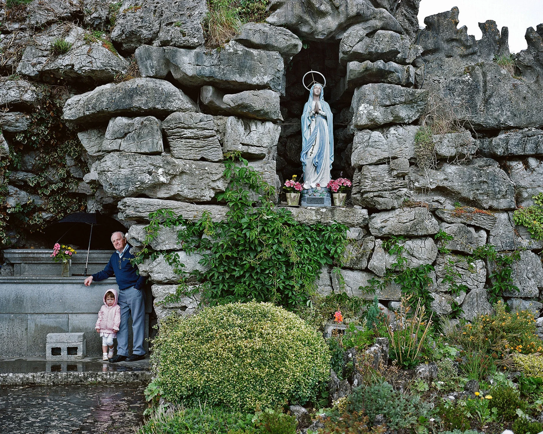 Though now a more secular society, Ireland still has remnants and relics of the old religious faith, even if many of its devoted followers are typically advanced in age – part of what might be termed a dying generation. The Catholic Church had been one of the country’s mainstays. Falling Mass attendances, declining priest numbers and various damaging scandals have shaken the institution and weakened its grip. Despite this my father is a daily Mass-goer; his faith doesn’t appear to have flinched. The house where I grew up in the west of Ireland is where my father now resides with his wife and their daughter Susan; all the rest of the family have flown the nest, some starting families of their own, one in New York where she has become part of the Irish Diaspora. The religious paraphernalia located throughout this house gives God a central presence and status not uncommon in Ireland at the time. We prayed as a family, like when the Angelus bells struck at noon and six in the evening. We knelt at night to say the Holy Rosary. Many of our rites of passage as children were rooted in Catholicism – our first communion, our confirmation, and so on. My father, who is 85, would not have seen anything remarkable in this. He was merely carrying on the tradition of his own father’s generation. Having spent half his life working, he recently retired, closing his drapery store. His undertaker’s business continues. For me and others in the family it meant that death was never far away or overtly mysterious. We became accustomed to the dead of our parish being prepared for the final ceremonies before burial. We would often come home from school to see who had died that day. If we truly wanted to make our father proud, we would have mastered the game he followed all his life: hurling. This ancient Irish sport, requiring great dexterity, courage and speed, can still weave a spell on him. Born in a rural community he has seen his own life change and now that of his children too. In recent years he lost a brother to whom he was close. Now I see him deriving great joy from his grandchildren. In their company he seems tranquil. At peace. His work done.