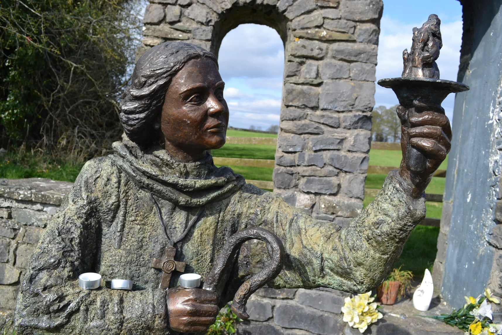 The statue of St Brigid (also known as St Bride) at St Brigid's Well, Kildare, Ireland. She is depicted holding a flame to represent the eternal flame that burned at the heart of the mixed gender abbey she built in the fifth century.