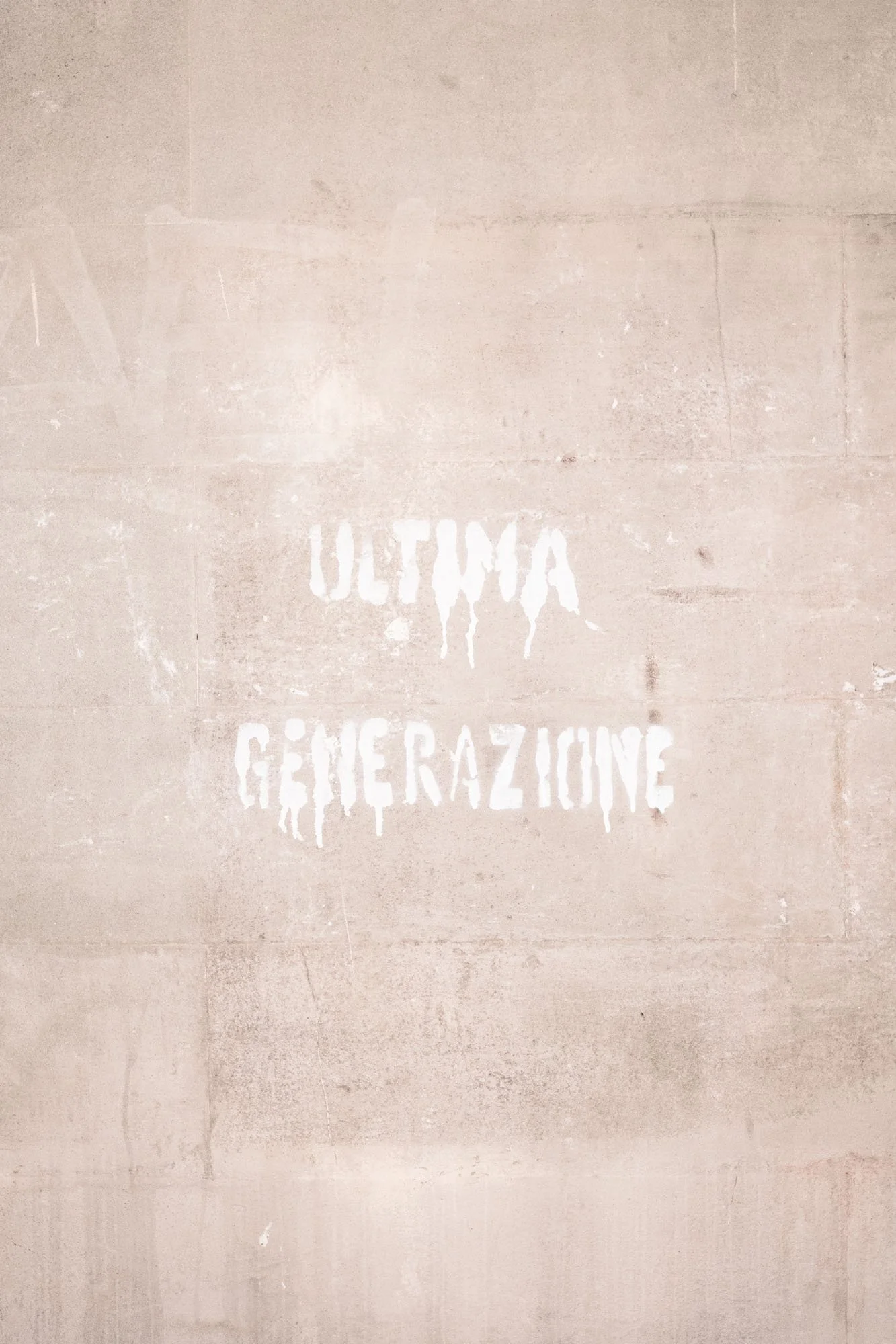 Graffiti sur un mur en béton avec les mots "ULTIMA GÉNÉRAZIONE" en lettres blanches, style graffiti.