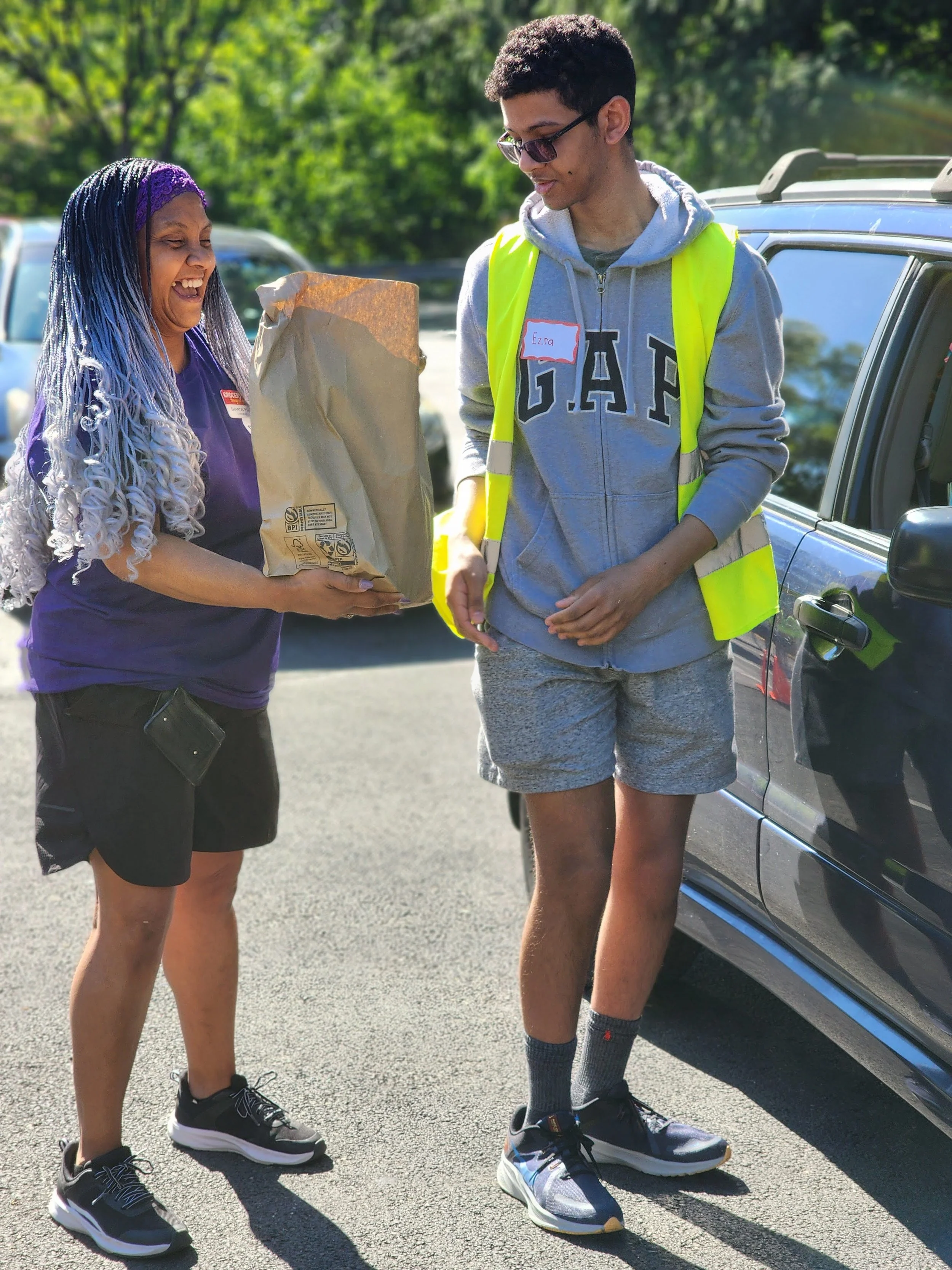 Two volunteers carrying a bag to a car
