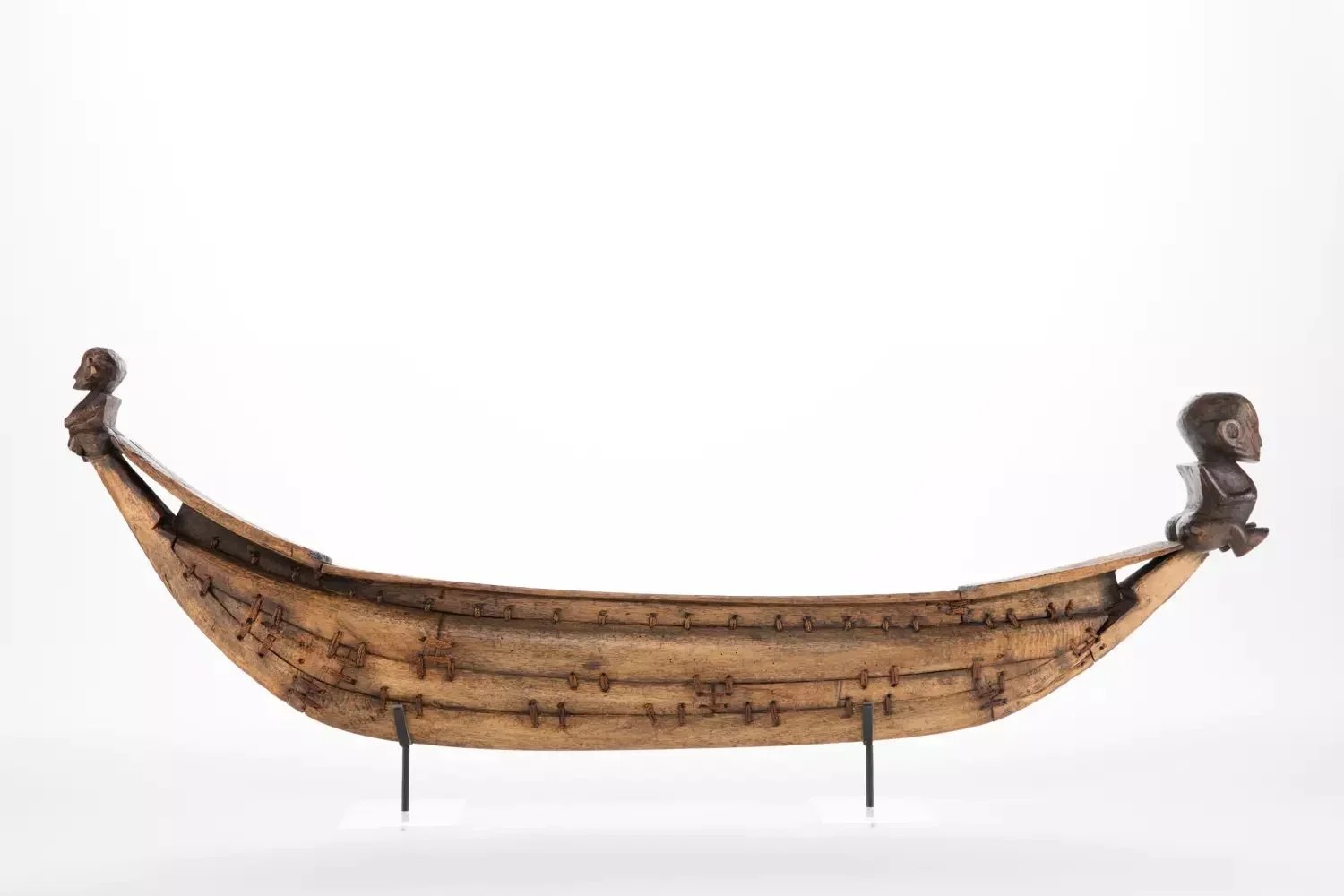  A fully planked canoe model with the bow and stern extremities decorated with a tiki. The tikis should be looking inside the canoe. 