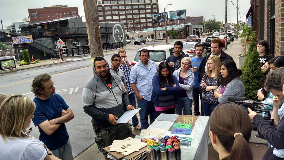 Giving a demonstration on how to properly use stencils, tape and spray paint to those who've never tried the medium before. 