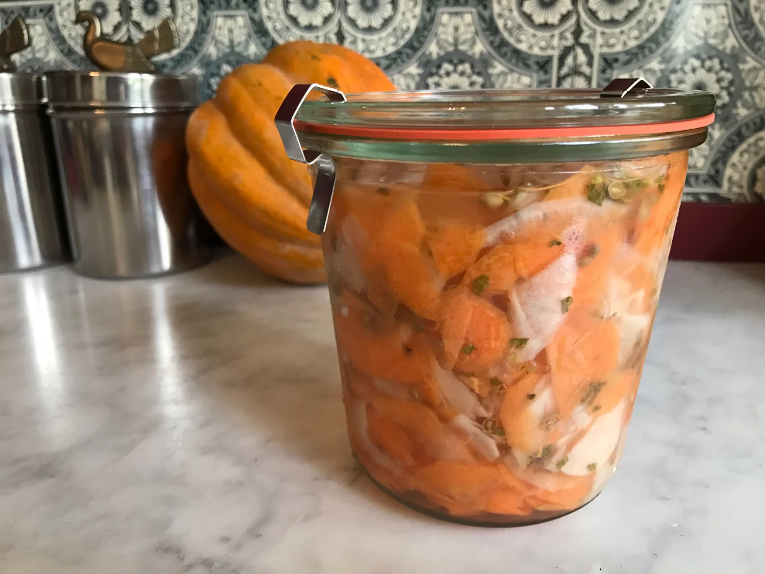 A jar of orange and white, gluten free and FODMAP Friendly quick pickled carrots and daikon sliced on a mandoline by Posh Belly's Kitchen.