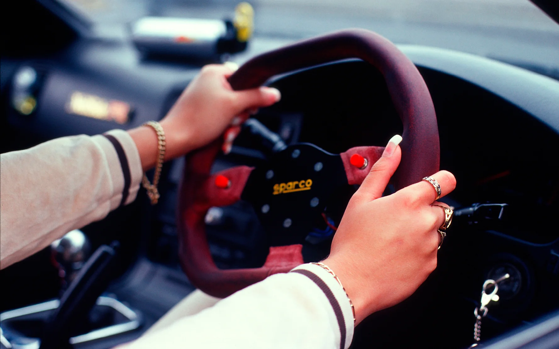 A girl with false nails, with her hands on the steering wheel of her car, Girlracers, Southend, UK 2004 © Naki / PYMCA