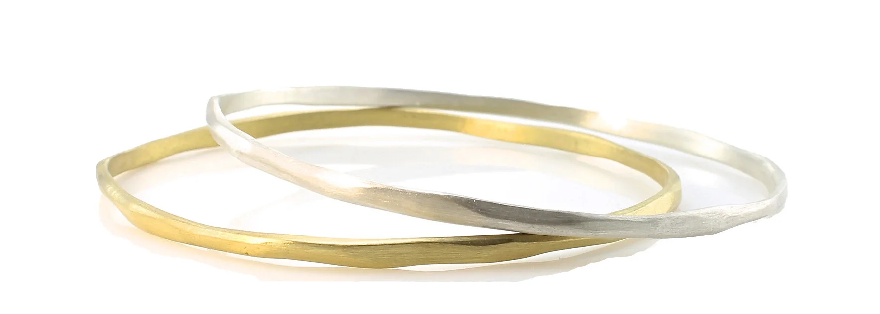 Thin, carved bangles in 18k gold and sterling silver