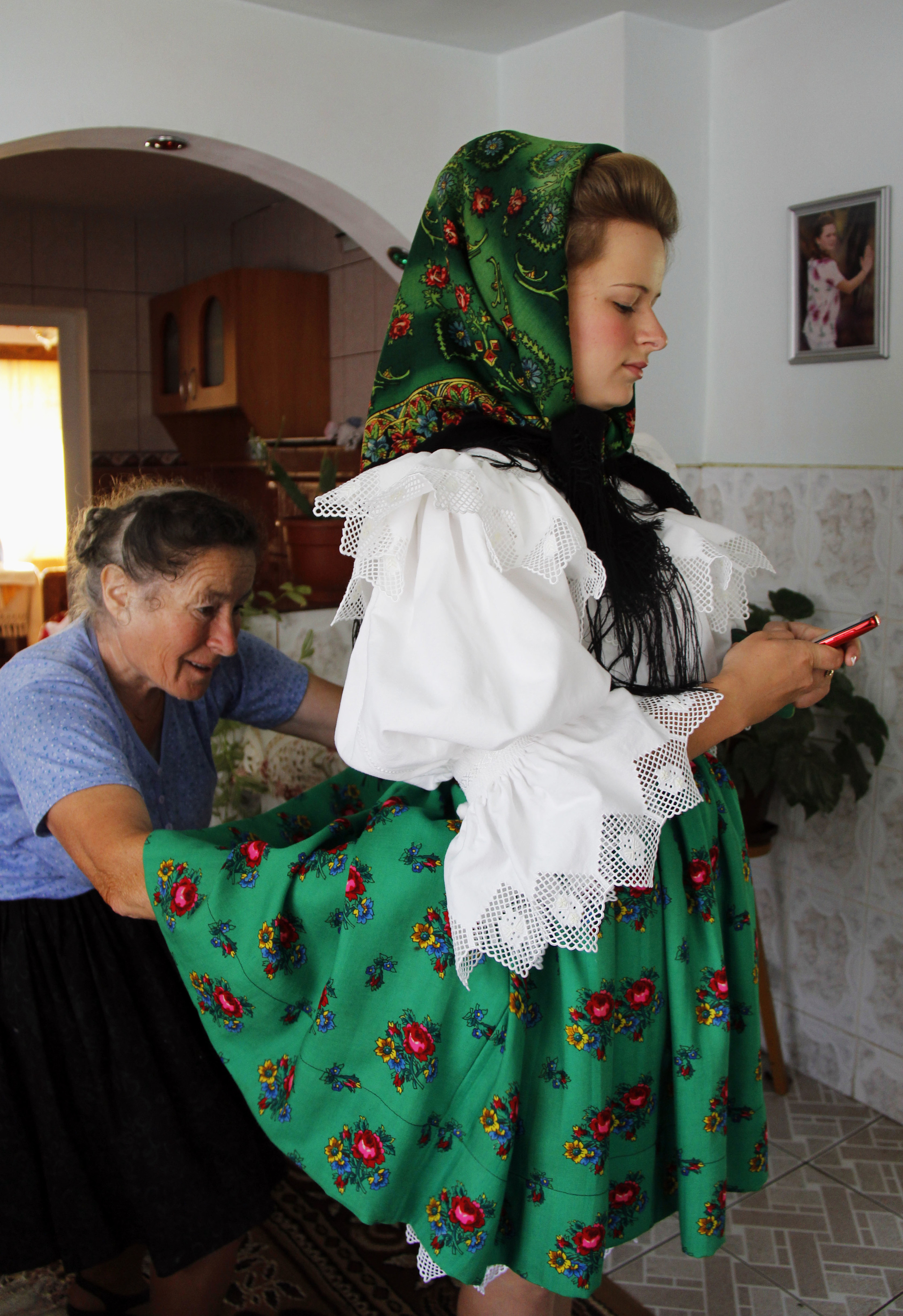 Marii's grandmother, Illiana, helps her add the finishing touches to her skirt before they leave for the St. Peter's Day parade and mass on June 29, 2014. Marii would not be able to have her cell phone with her the rest of the day due do her traditi