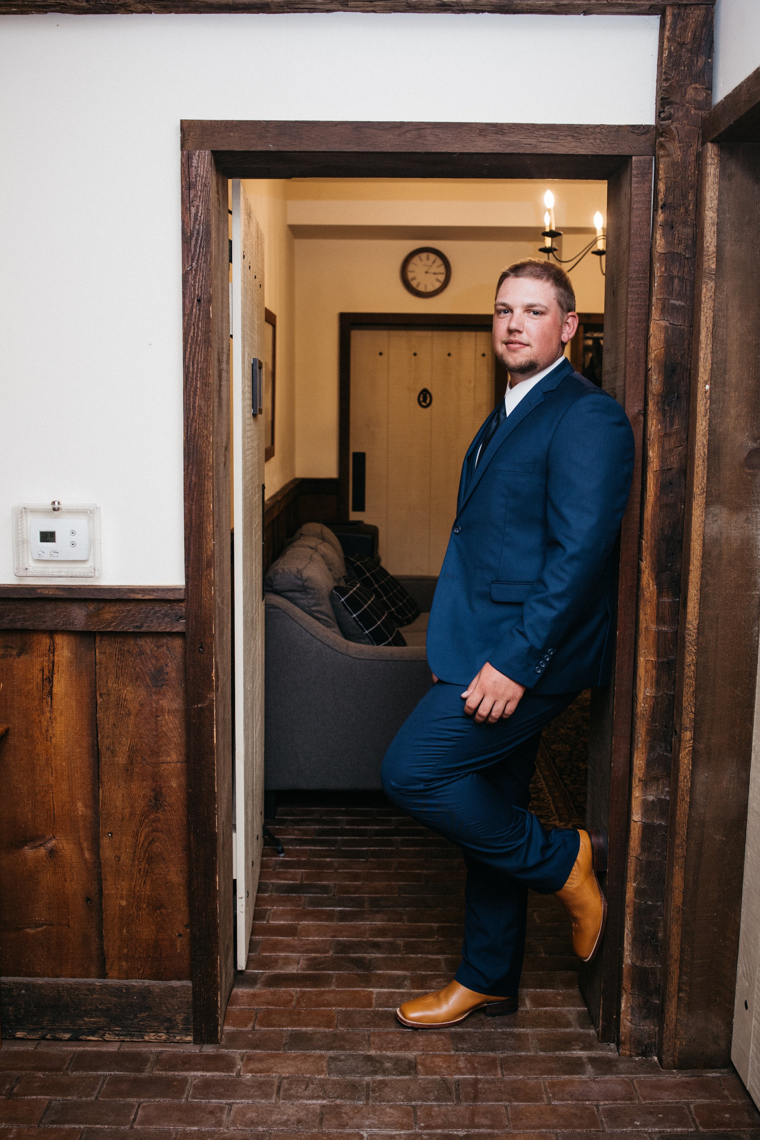 A portrait of the groom leaning against the wall.