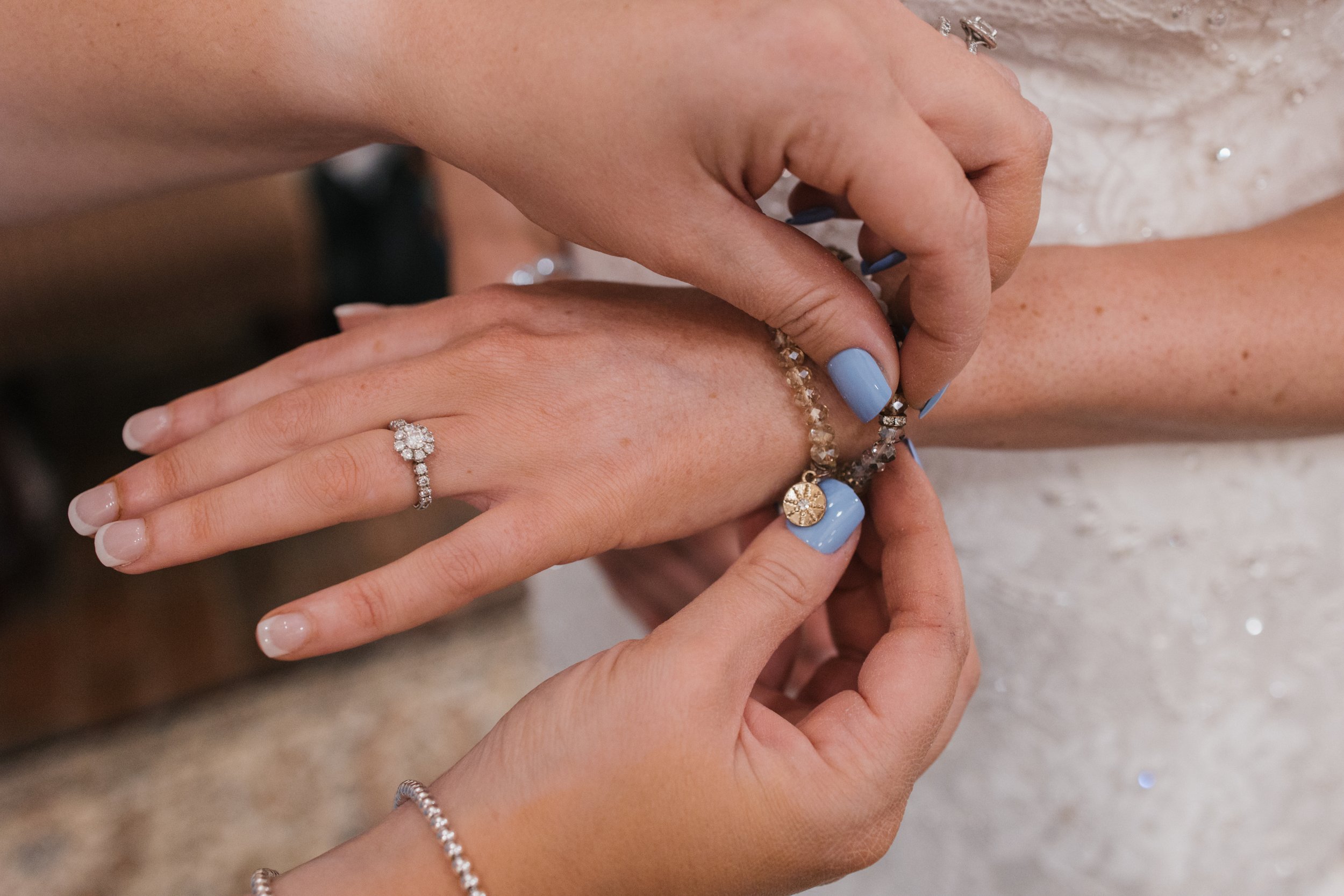 The maid of honor puts a bracelet on the bride.