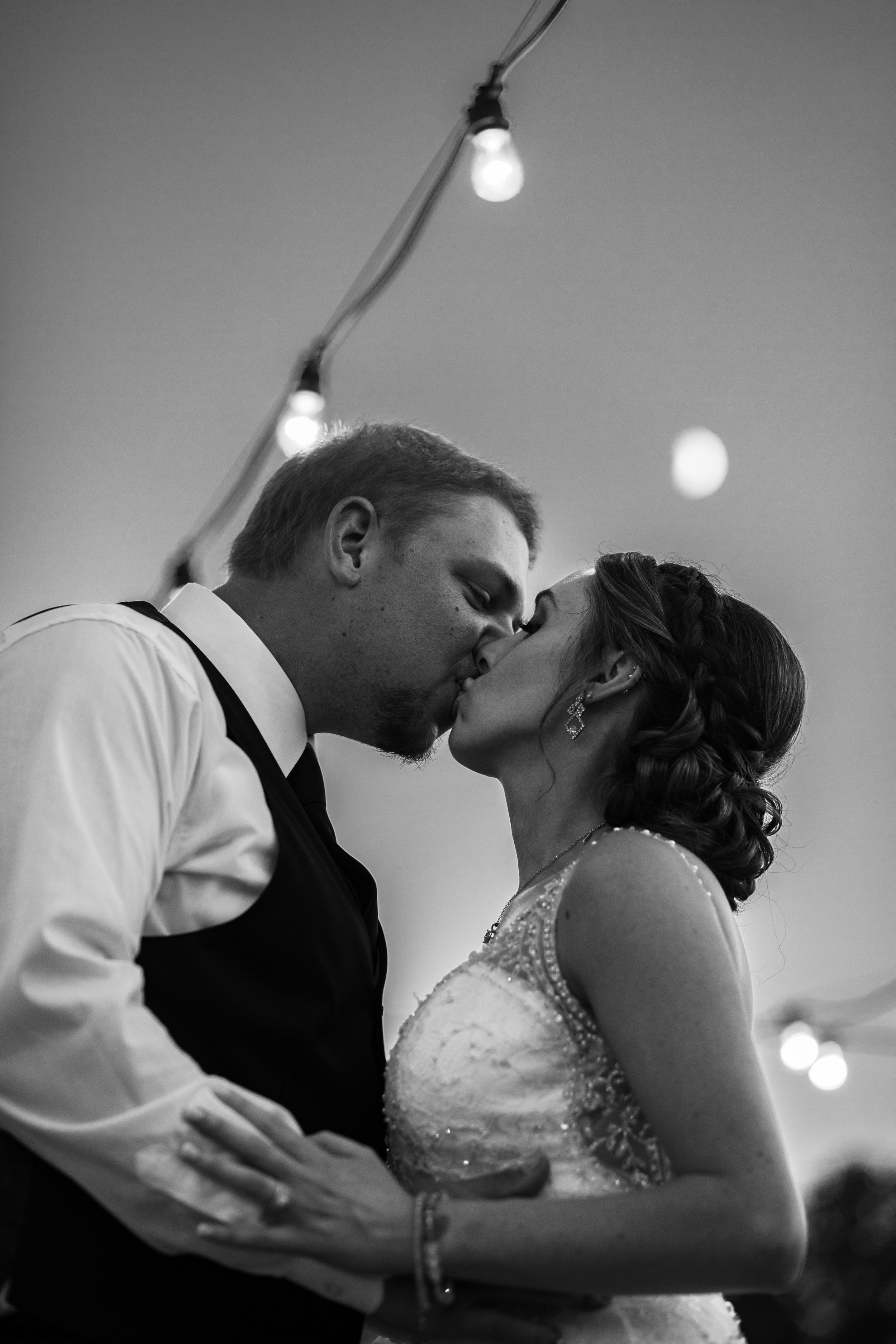 A portrait of a bride and groom under the moon, in black and white.