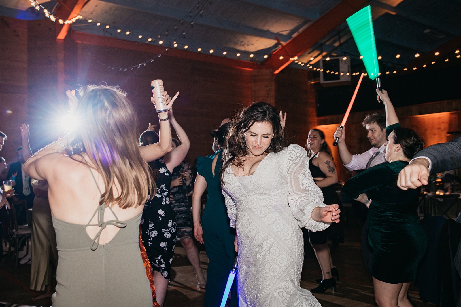 Dancing at wedding reception, with a green lightsaber in the background.