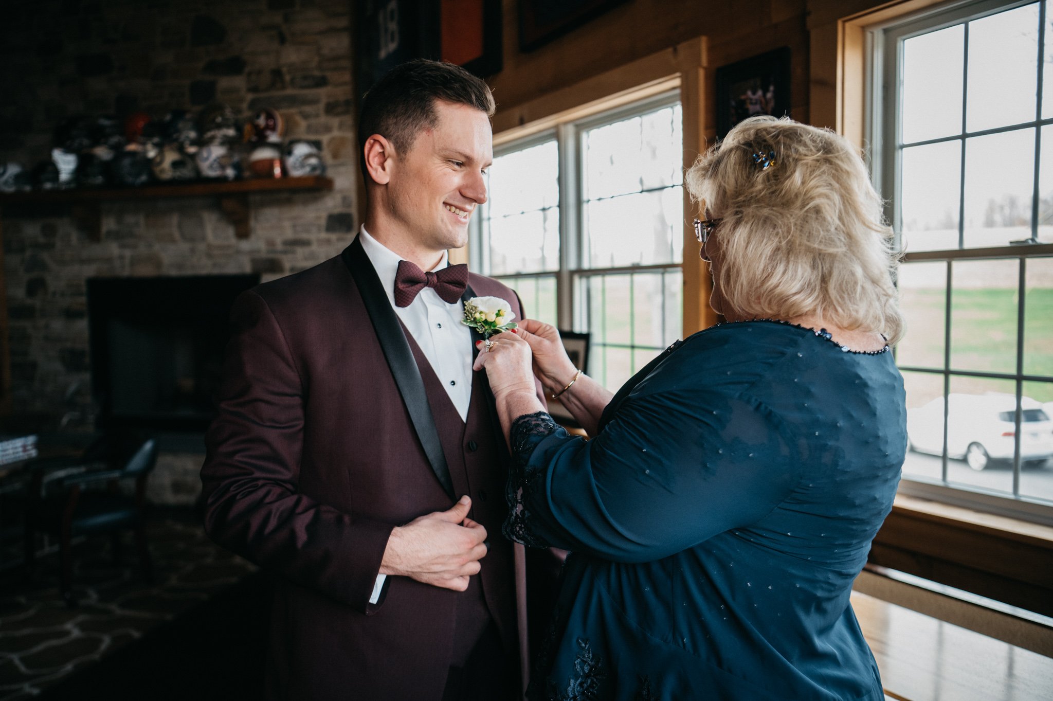 A grooms mom puts a boutonnière on her son.